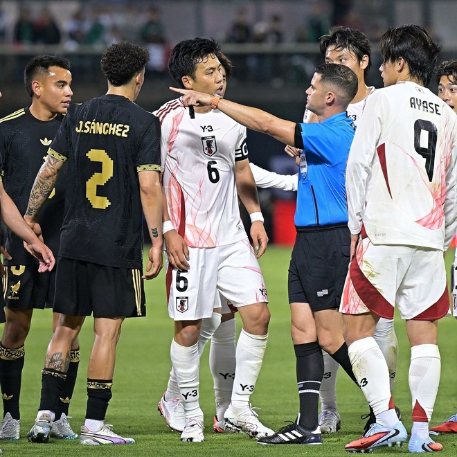 主審と会話する遠藤が思わぬ妨害行為にあった。写真：金子拓弥（サッカーダイジェスト写真部／現地特派）