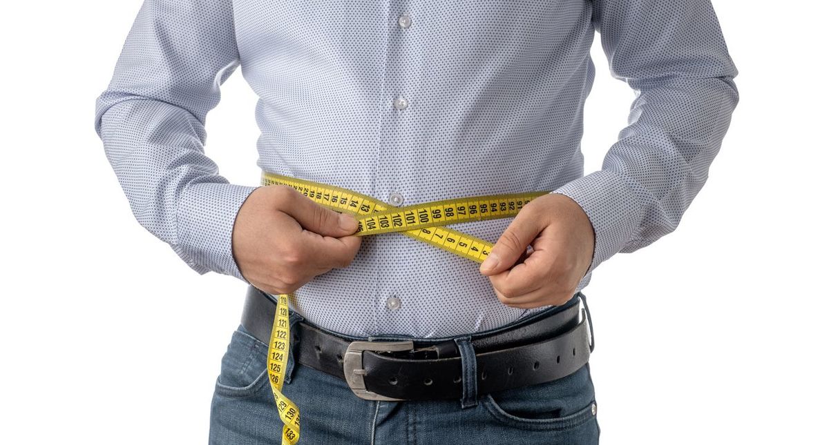 お腹周りを巻き尺で測っている男性