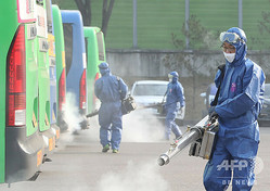 韓国・ソウルのバスターミナルで、新型コロナウイルス対策として消毒剤を散布する作業員ら（2020年2月20日撮影）。(c)YONHAP / AFP