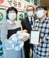 ７万人目の守谷市民となった尾高将基ちゃんを抱く母、文子さんと認定証を持つ父、将洋さん。後ろは松丸修久市長＝２１日、茨城県守谷市役所（篠崎理撮影）