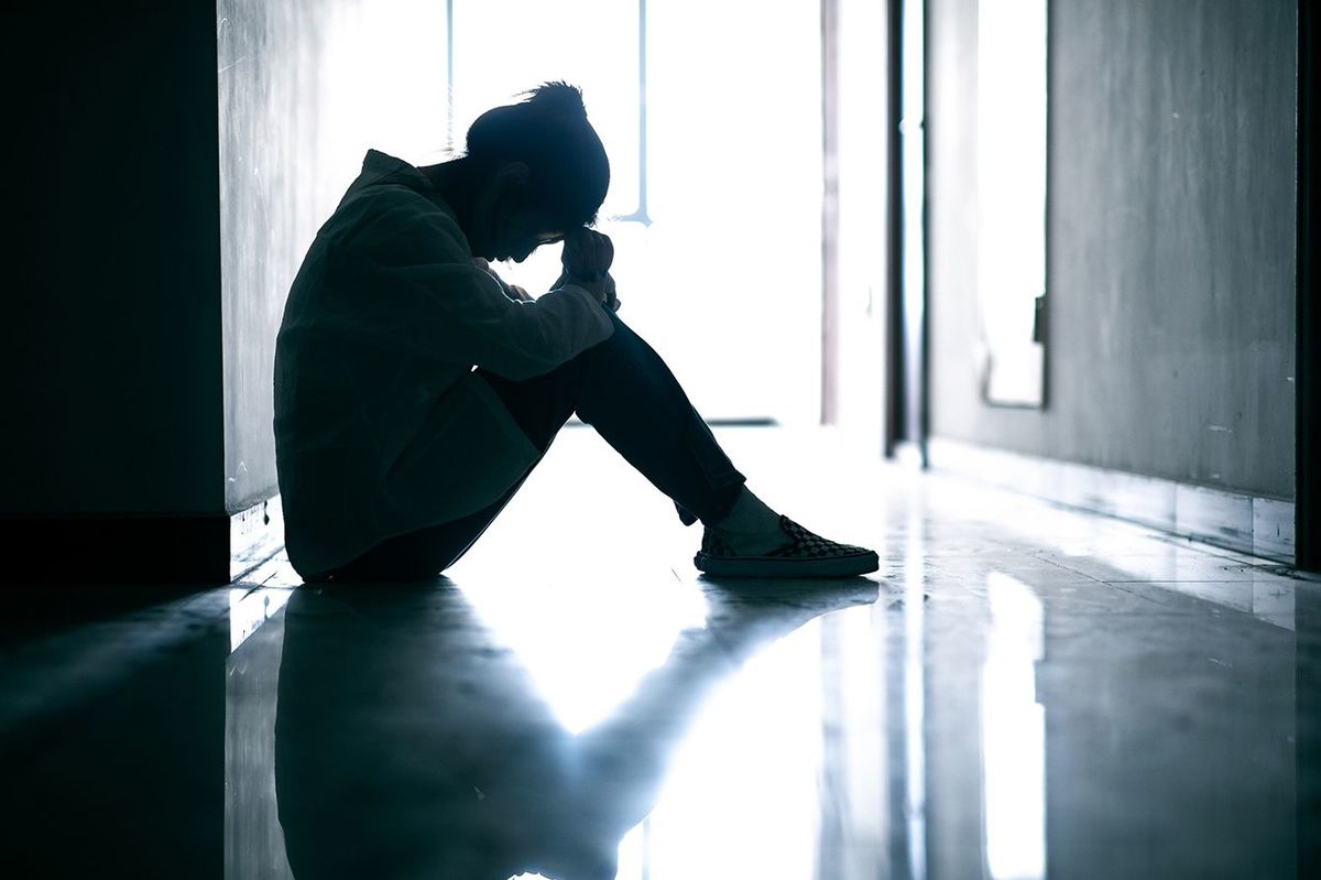 廊下の地面に座って落ち込んだ10代の女の子