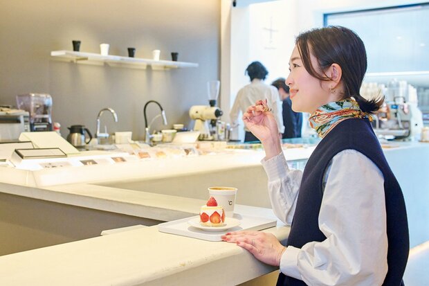 白が基調のカフェカウンターでいちごのケーキを食べる女性