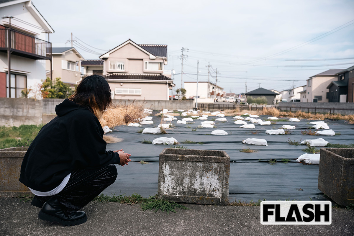  自宅の跡地に佇む林氏（長男）。2000年に放火のため全焼したが、壁の落書きを消した跡がいまも残る（写真・木村哲夫） 