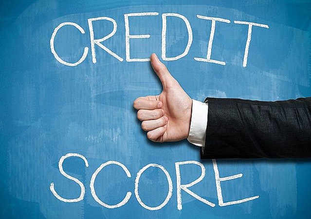 CREDIT SCORE と書いた黒板の前で親指を立てたハンドサイン