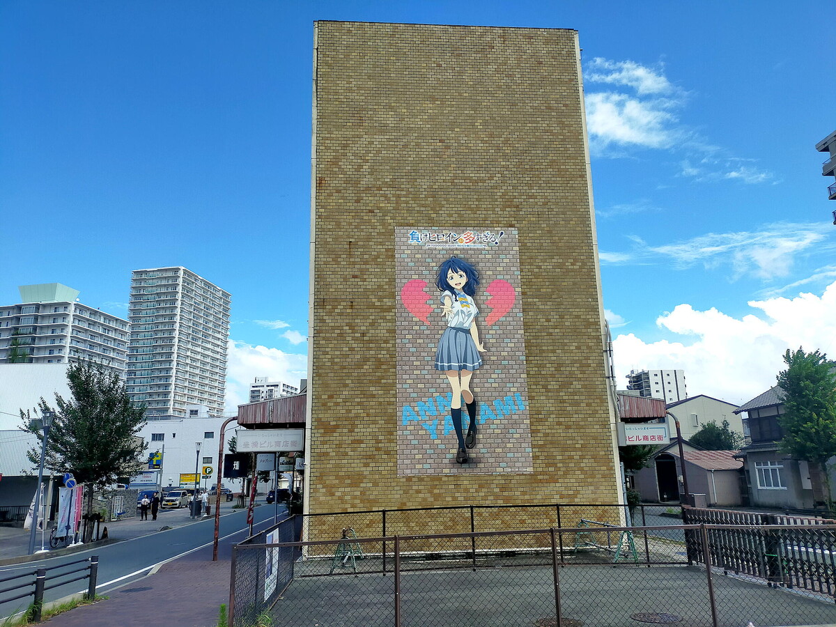 愛知県・豊橋市にある水上ビル。本作ヒロインの一人である八奈見杏菜の巨大なビジュアルに彩られている。