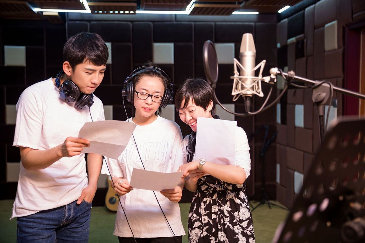 スタジオでボーカルを録音する若者たち